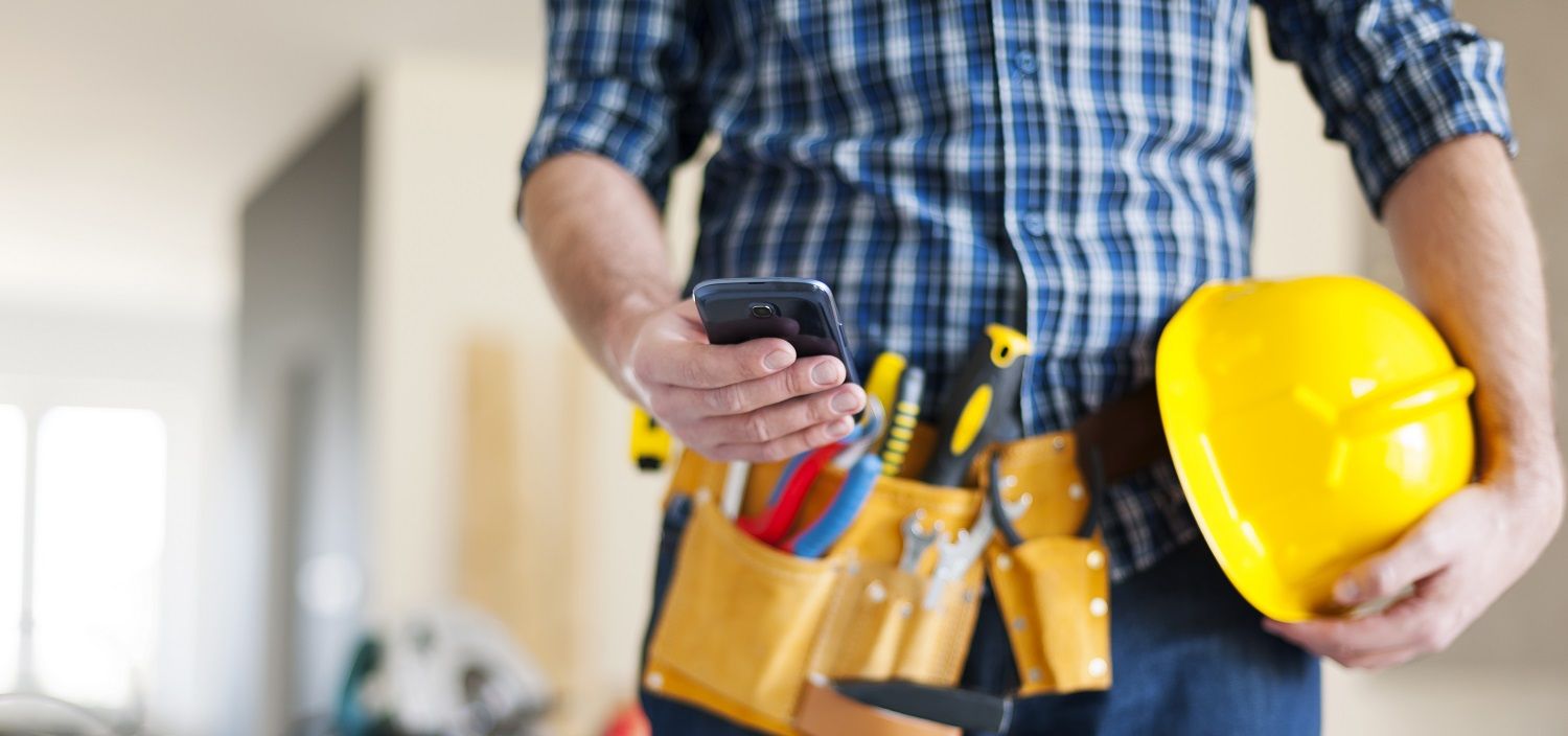 Imagen de hombre con móvil en la mano y herramientas de instalación y mantenimiento